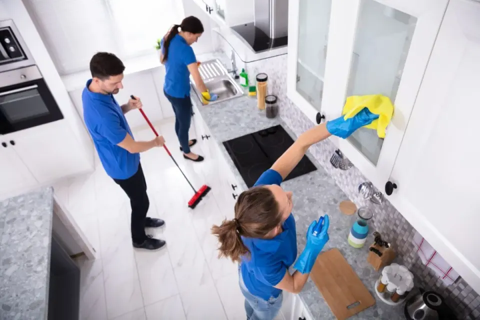 Tres profesionales de limpieza trabajando a la vez en la cocina de una vivienda