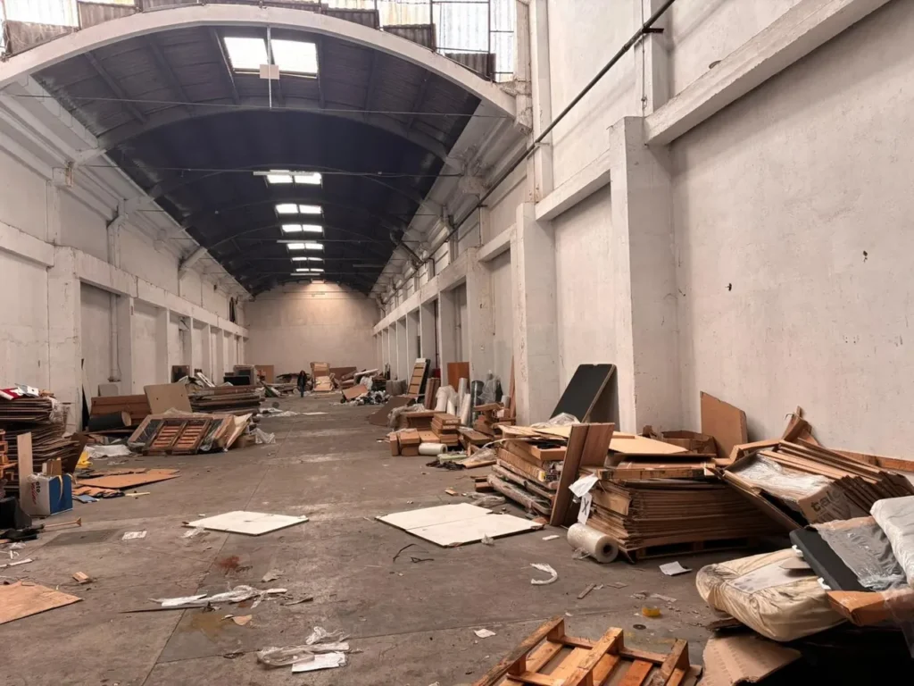 Nave industrial en Barcelona antes del vaciado, con palés, cartón y material acumulado por todo el suelo